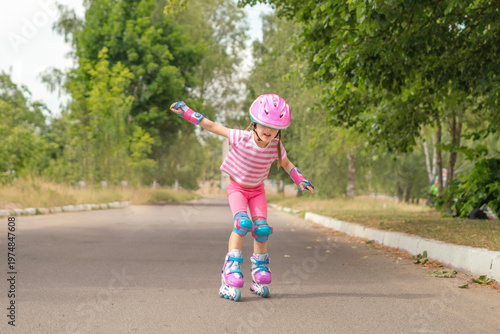 A little girl is trying to keep her balance while learning to rollerblade. Teaching children how to ride fast on roller skates