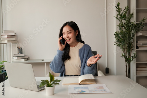 Young woman talking on smartphone working from modern office