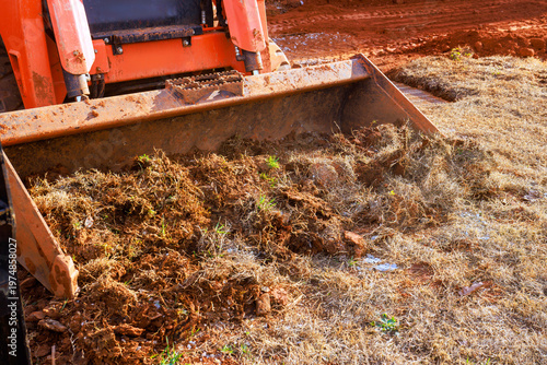 Heavy machinery works to move dirt debris in rural location during landscaping work with soil grass land clearing,