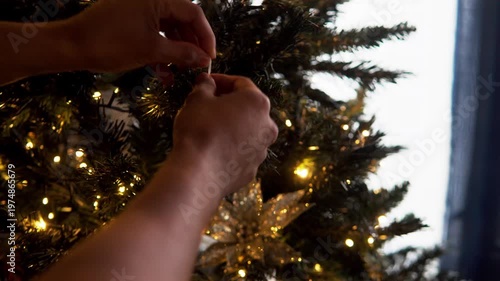 Person hanging snowy decoration on christmas tree