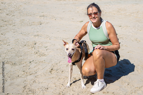 Active woman in her 50s with dog on sandy beach smiling outdoors