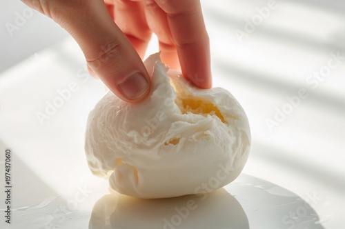 Fresh mozzarella cheese ball torn apart by hand revealing soft creamy texture