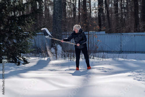 A woman clears snow from her plot of land.