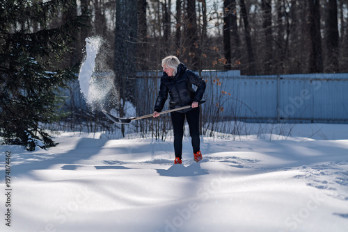 A woman enthusiastically removes snow.