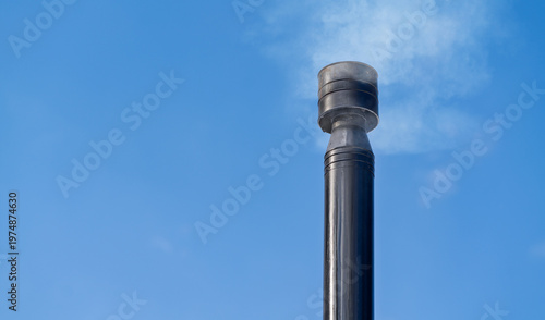 A chimney above a house with smoke coming out of it.