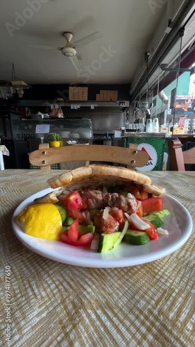 Traditional Greek pork souvlaki in pita bread with grilled vegetables. Tomato and cucumber salad at a Greek gyros taverna.