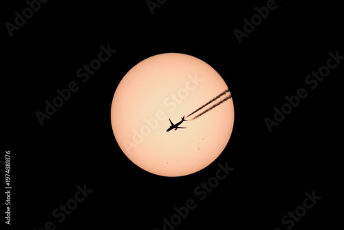 Silhouette of twin engined passenger jet plane  passing across the sun en route from Paris to Alicante