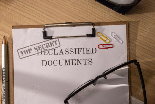 Top View of Declassified Top Secret Documents on a Clipboard with Glasses
