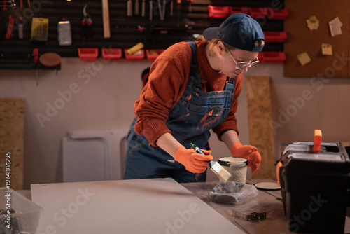 Obraz na płótnie Female restorer preparing to paint and renovate furniture with white paint in wo
