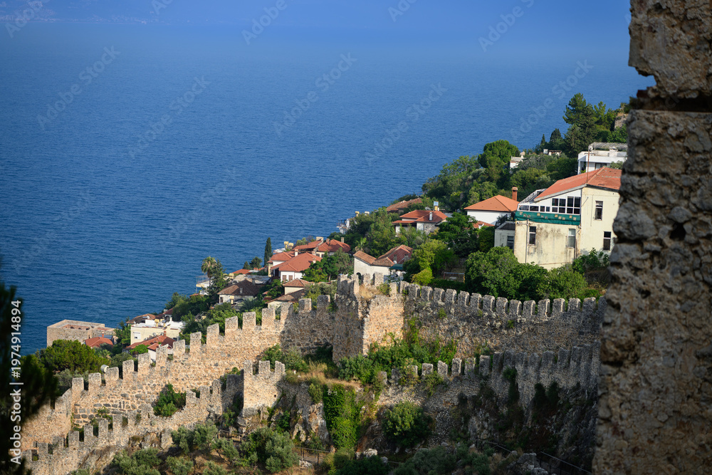 Naklejka premium Ancient stone walls of Alanya Castle overlooking Mediterranean Sea, Turkey. Medieval fortress architecture, coastal city heritage, scenic travel destination, historical fortification concept