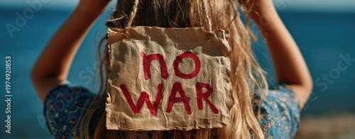 Girl with 'no war' sign in front of blue water