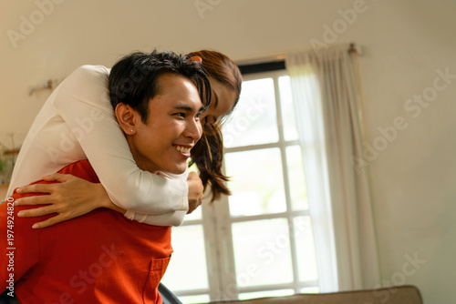 Playful Young Asian Couple Enjoying a Piggyback Ride at Home
