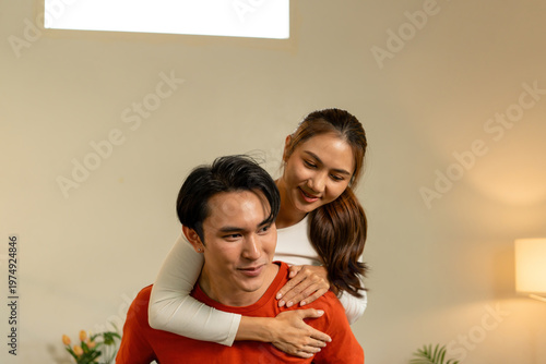Playful Young Asian Couple Enjoying a Piggyback Ride at Home