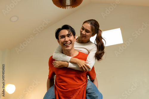 Playful Young Asian Couple Enjoying a Piggyback Ride at Home