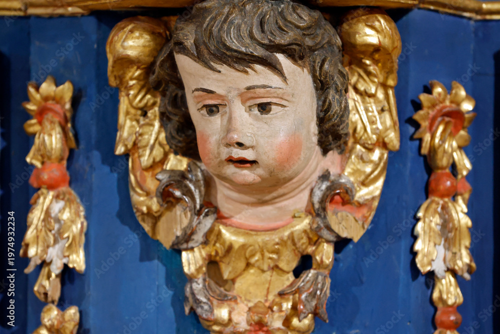 Fototapeta premium Baroque chapel of La Gruvaz after restoration. Carved angel head emerges from ornate golden frame of the chapel retable. Saint Gervais. France.