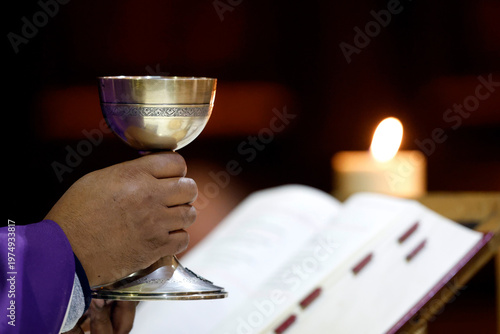  Eucharist celebration.  Priest in purple vestments firmly holds an ornate consecrated chalice during the Eucharist.  Thones. France.