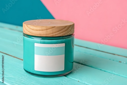 Turquoise scented candle in glass jar with wooden lid on a table