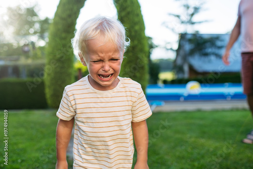 Принти на полотні Crying toddler boy standing in garden with strong emotion.