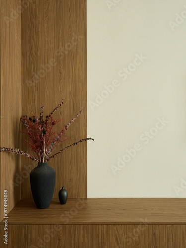 Minimalist interior decor with a black vase holding dried branches on a wooden surface. Wood panel and beige wall background. Modern home design.