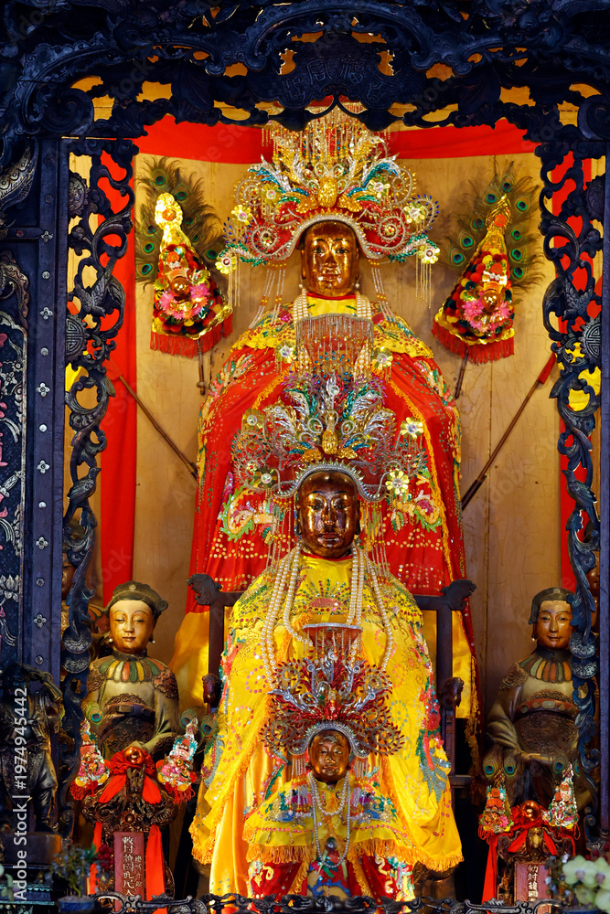 Fototapeta premium Ba Thien Hau Temple. Ornate wooden shrine with lacquered carvings frames three golden Taoist deity statues. Ho Chi Minh city. Vietnam.