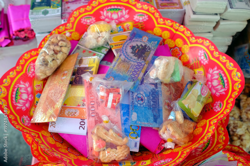 Fototapeta premium VRed lotus tray filled with votive paper money, snacks and miniature goods for ancestor offerings. Ho Chi Minh city. Vietnam.
