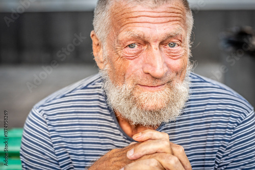Elderly man with beard smiling in casual striped shirt outdoor portrait showing warm expression