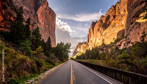 Scenic desert road between tall rock formations, leading to distance under cloudy sky on a bright day