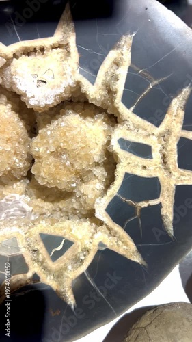 A large black geode stone sawn in half with yellow bright crystals inside, the camera moves smoothly along, showing the entire stone. The concept of mineralogy, stone science, archaeological finds