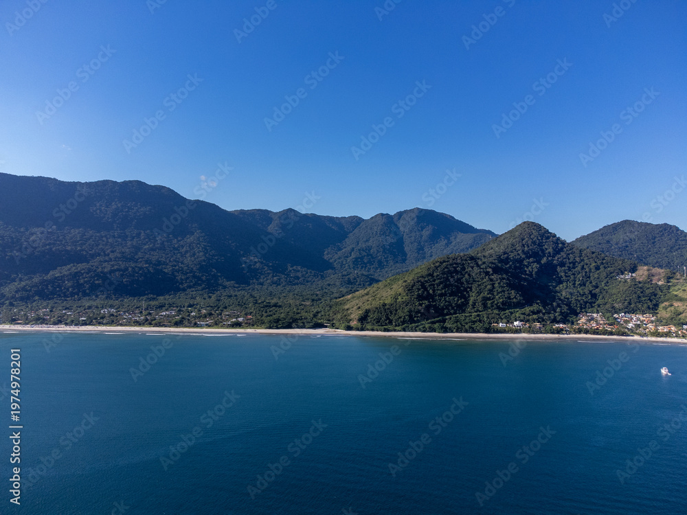 Fototapeta premium Aerial wide view of Guaeca beach and Rio-Santos highway winding through lush green mountains in Brazil