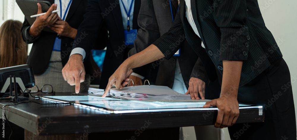 Fototapeta premium Business team planning project, hands pointing at documents on a table. Concept of corporate collaboration, strategic data analysis, and professional teamwork during a creative meeting