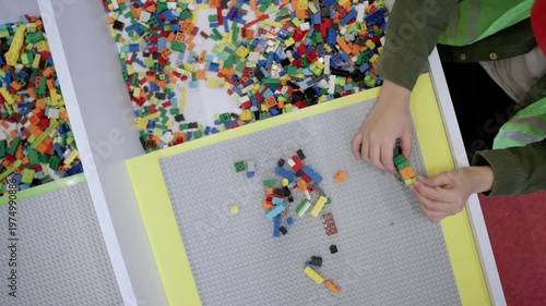 Educational toys for young children. Top view of little boy playing with toy blocks on the table in educational gaming center. Slow motion