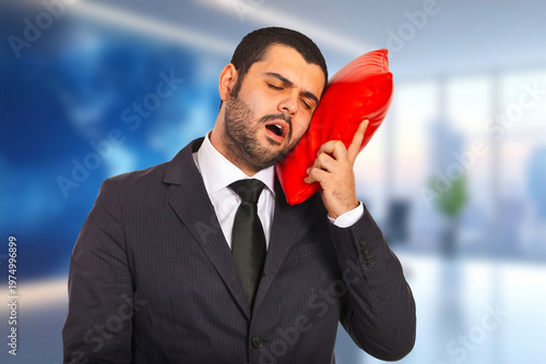 Man in suit holds red pillow to head