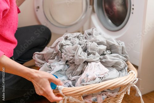 Person loads wrinkled clothes into washing machine at home in the evening time