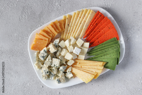 Cutting a variety of elite cheese on a white plate, Top view