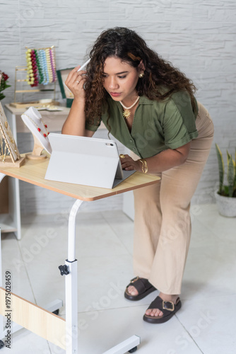 Woman jewelry designer creating on tablet in workshop