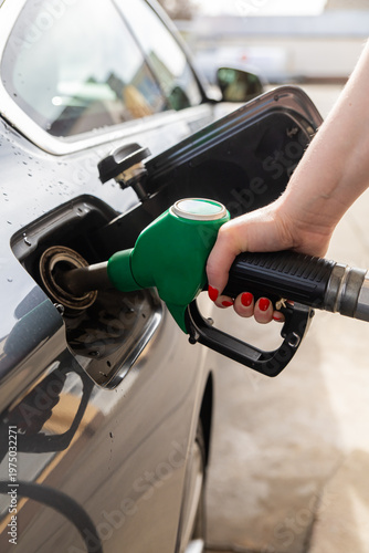 Closeup of woman pumping gasoline fuel in car at gas station