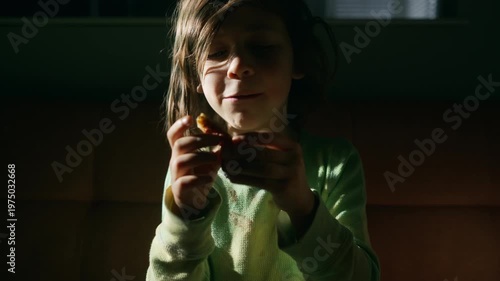 Boy with a messy face eating pizza on movie night