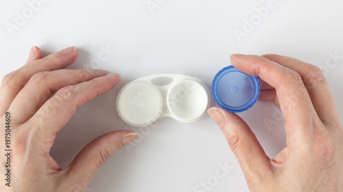 Bild auf Leinwand Human hands unscrew the lid of a contact lens case