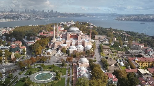 Close aerial view of Hagia Sophia mosque with Sultanahmet Square fountain garden tourists and Topkapi Palace, Bosphorus skyline in background, Istanbul