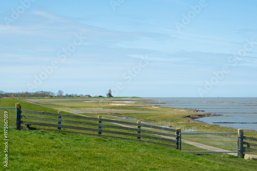 View over the salt marsh and along the dike towards the village of Wierum in Friesland, the Netherlands