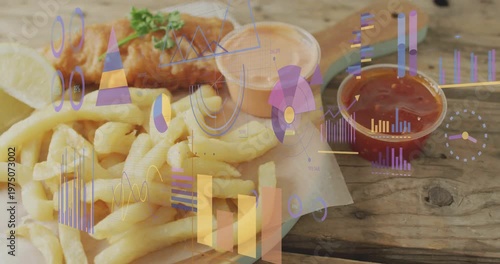 Panning camera revealing plate with fried fish and fries lemon at wooden table with charts moving