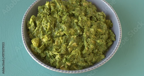 Chunky guacamole - famous Mexican avocado salsa in a blue bowl on a blue background. 