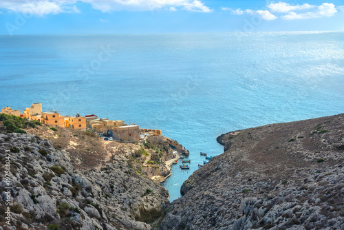 View from cliffs on cove with trip boats at fishermen's harbour on south east coast of Malta