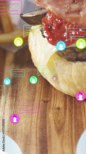 Vertical video: Top bun dropping starting burger stack as tongs placing bacon on board for promo