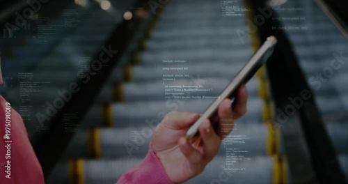 hand holding smartphone capturing escalator, displaying C++ code overlay for technology insight