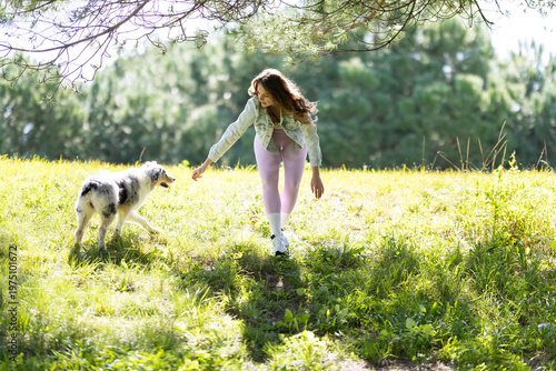 Young woman walking with a merle dog in nature