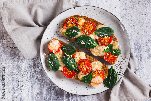 Close u of baked sandwiches with mozzarella, tomatoes and spinach on a plate top view