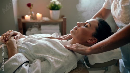 A serene woman lies on a massage table as a skilled therapist gently massages her neck, promoting relaxation and wellness in a peaceful setting.