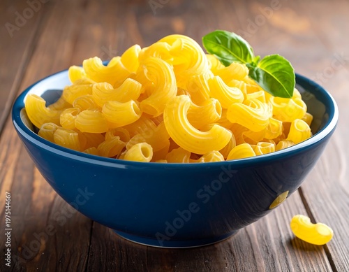A vibrant shot of cooked elbow macaroni pasta in a deep blue bowl, with a fresh basil leaf on top, set on wooden surface