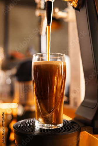 Quadro su tela Dark stout beer in glass with creamy foam on bar counter
Draft dark beer pouring